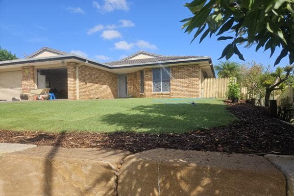 Forest mulch applied around garden bed next to freshly laid lawn in front of suburban home