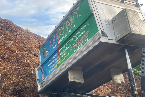 Angry Ant truck unloading forest mulch next to a large mulch stockpile